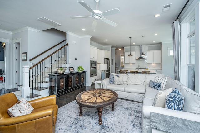 living room with a ceiling fan, stairway, recessed lighting, dark wood-style flooring, and ornamental molding