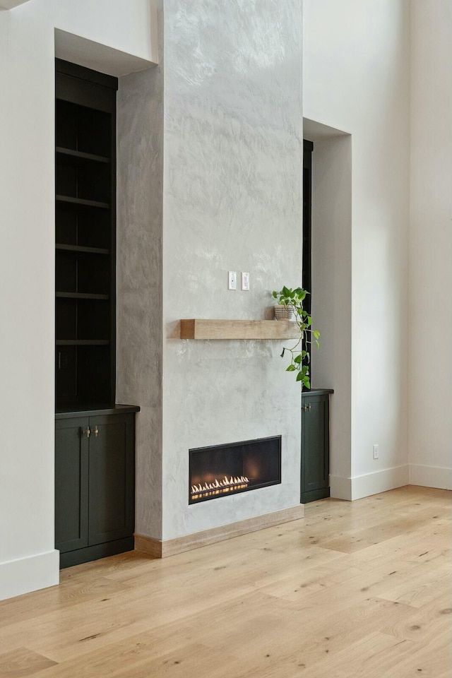 unfurnished living room with a fireplace, built in shelves, and light wood-type flooring