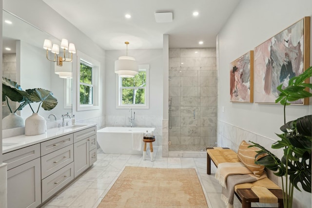 full bathroom featuring a freestanding bath, a sink, tile walls, marble finish floor, and a stall shower