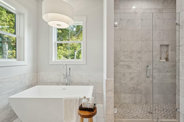 bathroom featuring a shower stall, a freestanding tub, and tile walls