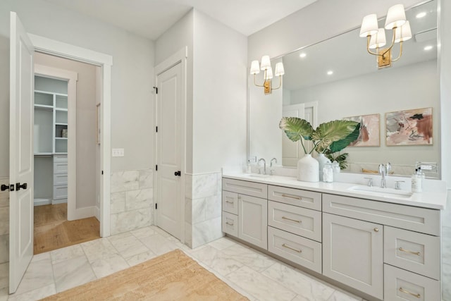 full bathroom with a chandelier, double vanity, marble finish floor, and a sink