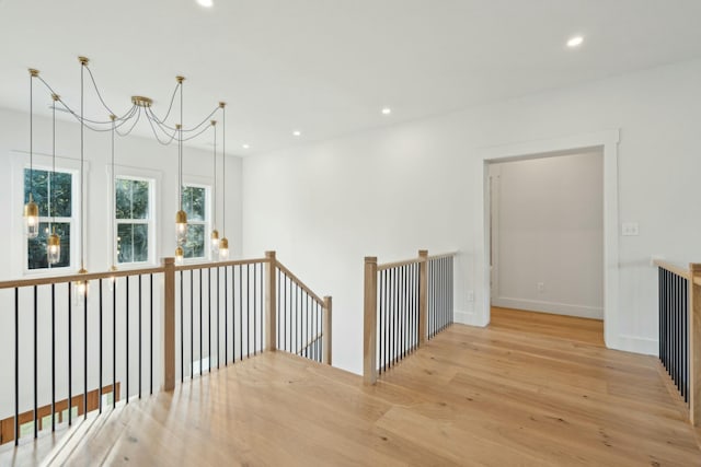 corridor featuring light hardwood / wood-style floors and an inviting chandelier