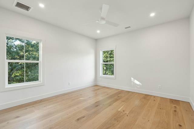 empty room featuring light wood-type flooring, ceiling fan, and a healthy amount of sunlight