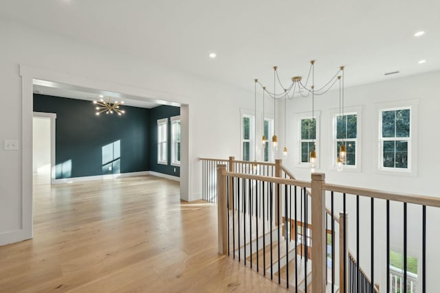 hallway with light hardwood / wood-style flooring and a chandelier