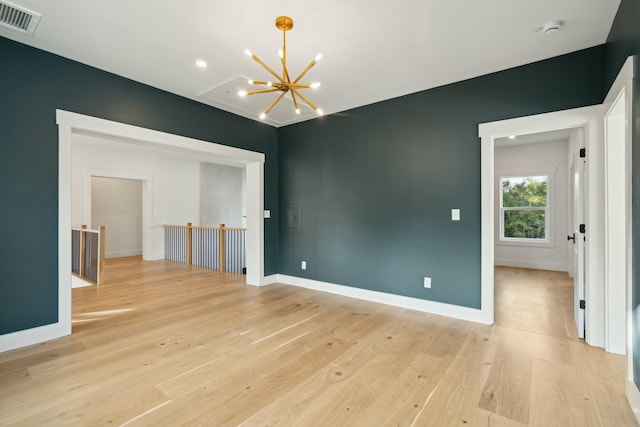 spare room with light hardwood / wood-style floors and an inviting chandelier