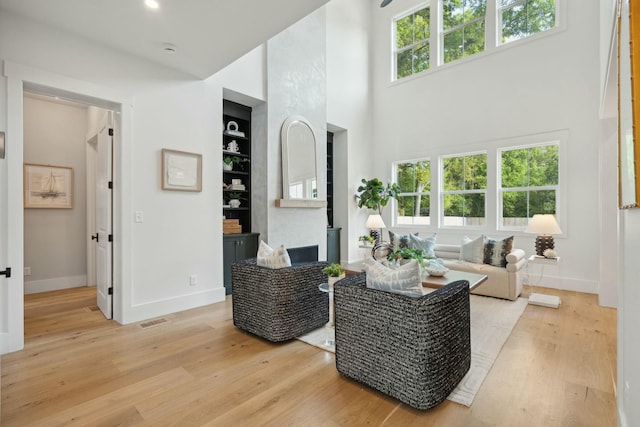living room with wood finished floors, baseboards, built in shelves, and visible vents