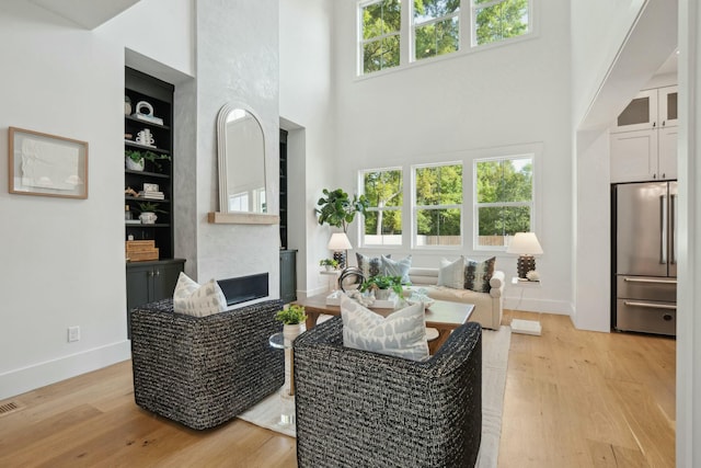 living room with light wood-type flooring, baseboards, built in shelves, and plenty of natural light