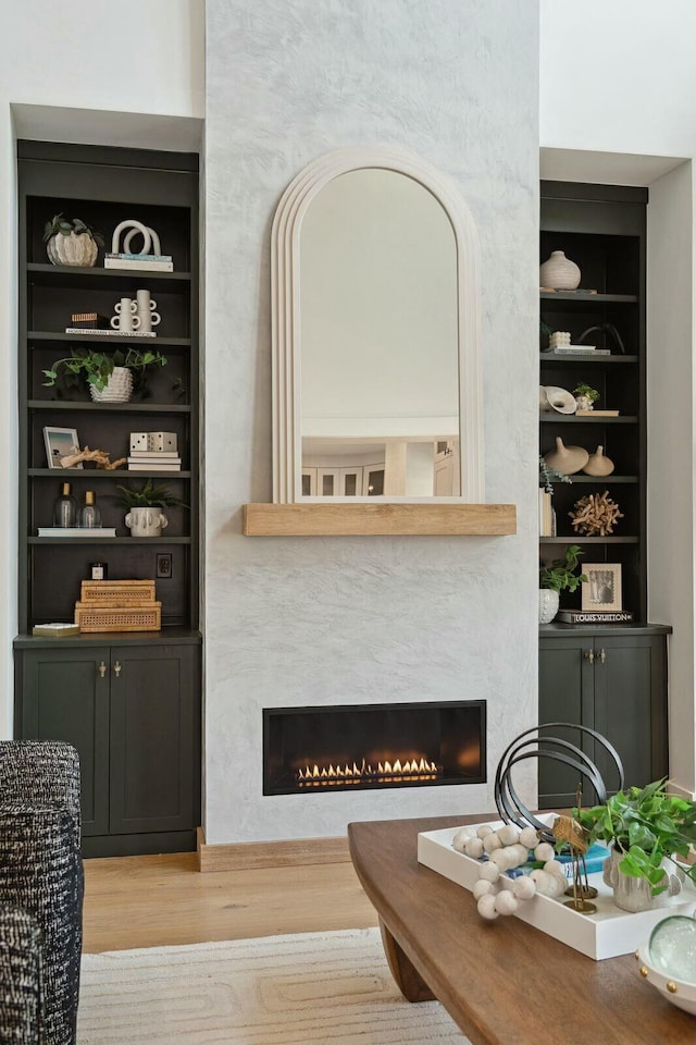 living room featuring built in shelves, wood finished floors, and a premium fireplace