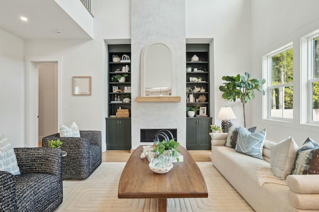 living area featuring built in features, a high ceiling, and a fireplace