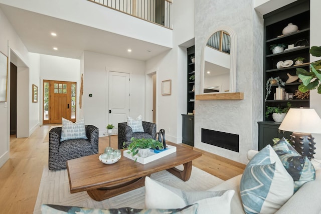 living area with baseboards, built in features, and wood finished floors