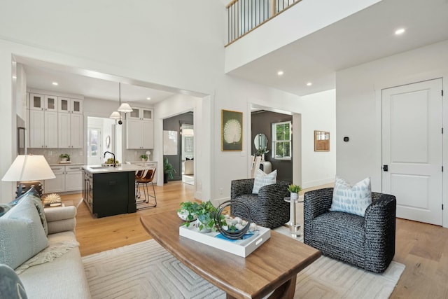 living area featuring light wood finished floors, a high ceiling, and recessed lighting
