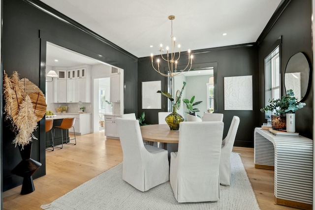 dining area with crown molding, light wood-style flooring, and a notable chandelier