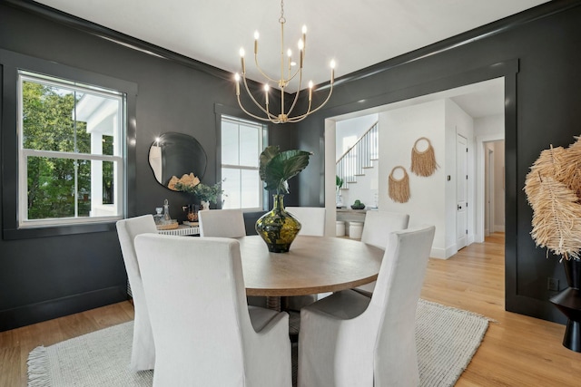 dining space with light wood finished floors, a notable chandelier, and baseboards