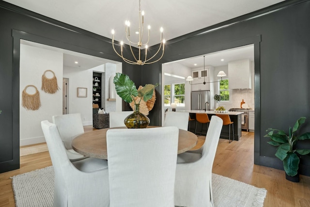 dining space featuring baseboards, light wood-type flooring, a chandelier, and recessed lighting