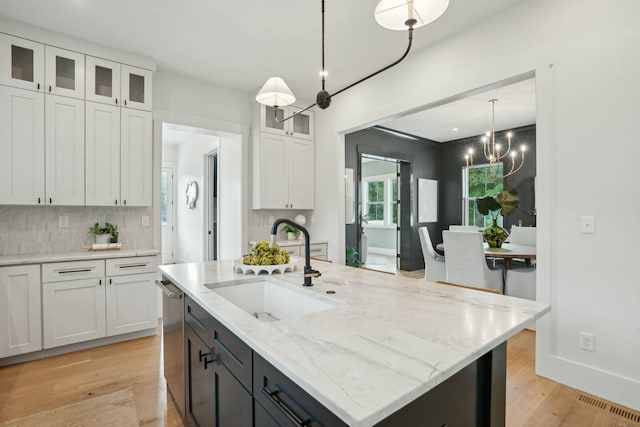 kitchen with light wood-type flooring, dishwasher, a sink, and white cabinets