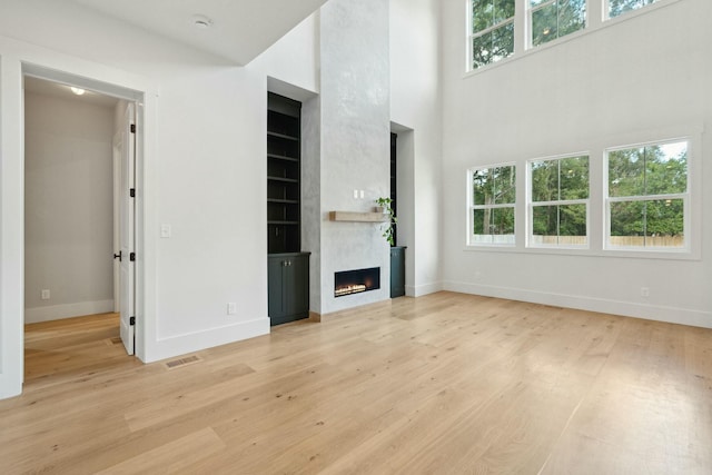 unfurnished living room featuring a large fireplace and light hardwood / wood-style flooring