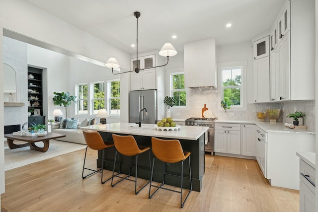 kitchen with premium appliances, custom exhaust hood, light wood-type flooring, and light countertops