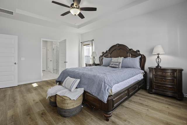 bedroom with ceiling fan, a raised ceiling, and light hardwood / wood-style flooring