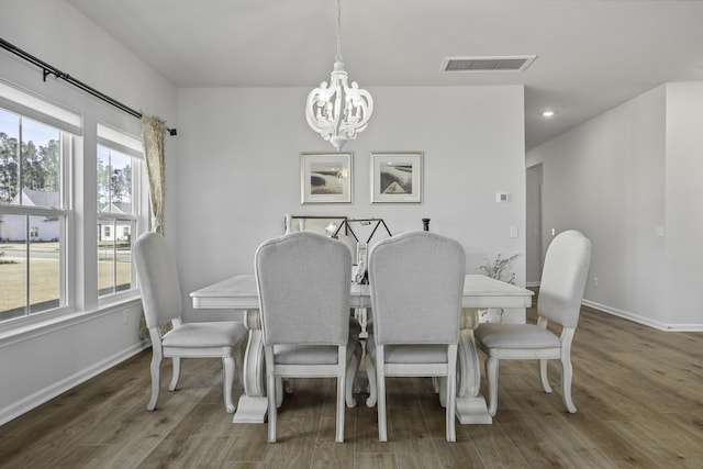 dining space with dark wood-type flooring and a notable chandelier