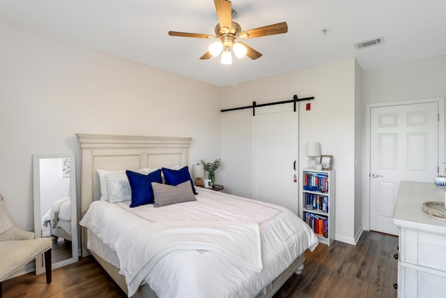 bedroom with dark wood-type flooring, a barn door, and ceiling fan