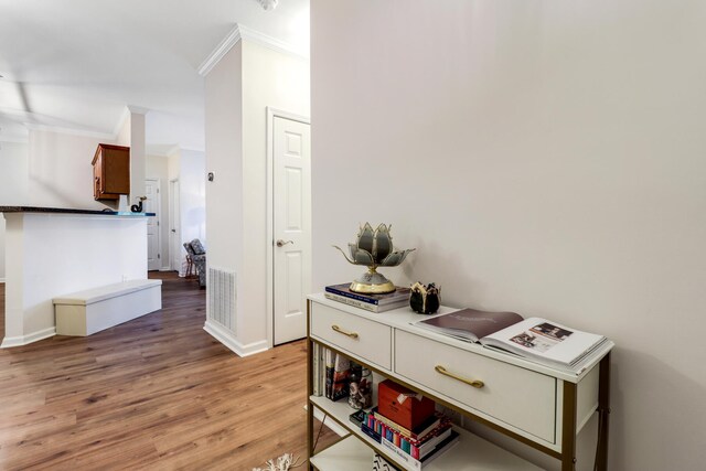 hallway featuring ornamental molding and light wood-type flooring