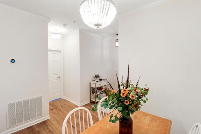 dining area featuring an inviting chandelier, ornamental molding, and wood-type flooring