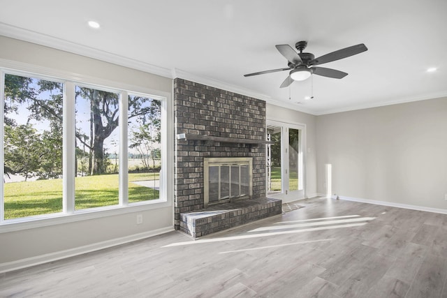 unfurnished living room featuring ceiling fan, ornamental molding, a fireplace, and light hardwood / wood-style flooring