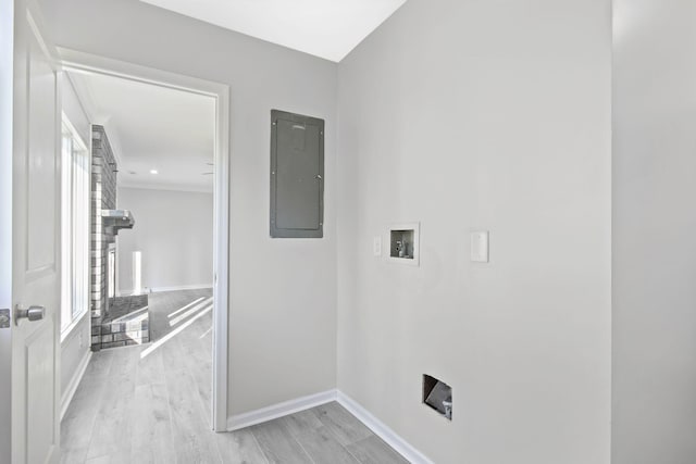 laundry area featuring hookup for a washing machine, a brick fireplace, electric panel, and light wood-type flooring