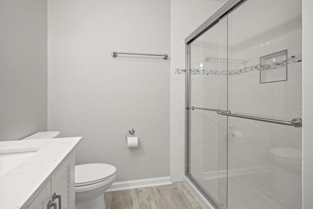 bathroom featuring vanity, hardwood / wood-style floors, a shower with shower door, and toilet