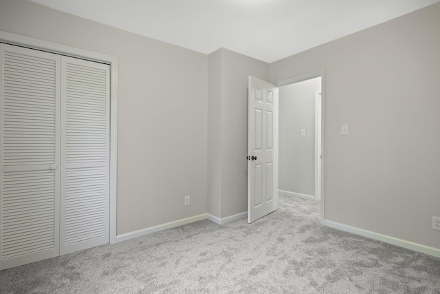 unfurnished bedroom with light colored carpet and a closet