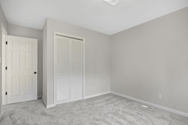 unfurnished bedroom featuring light colored carpet and a closet