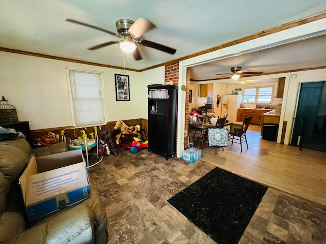 living room with hardwood / wood-style flooring, crown molding, brick wall, and ceiling fan