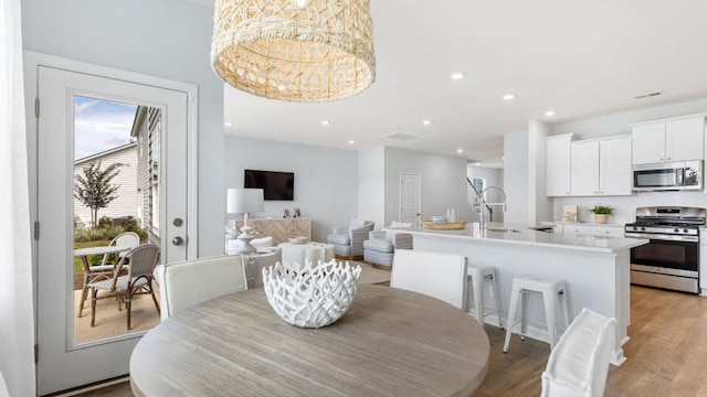 dining room featuring a chandelier, visible vents, light wood-style flooring, and recessed lighting