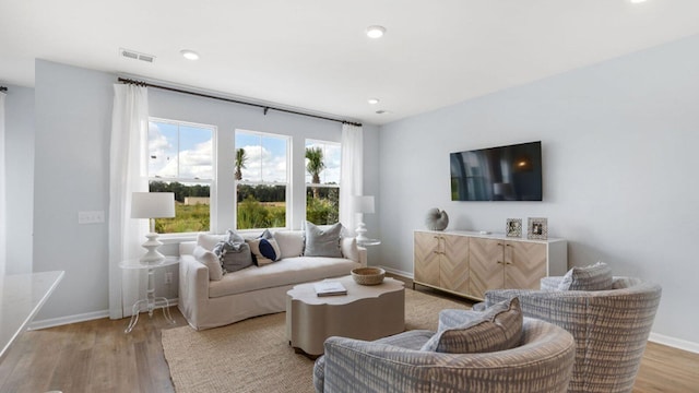 living room featuring light wood-style floors, baseboards, visible vents, and recessed lighting