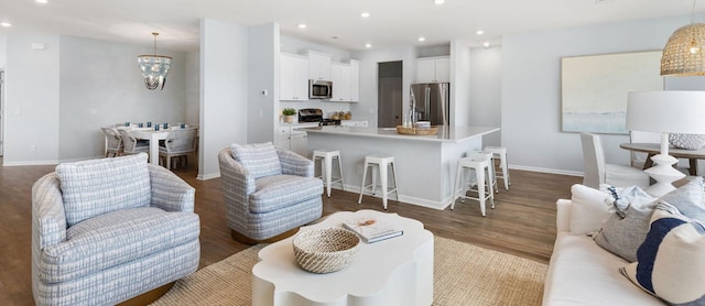 living area with recessed lighting, baseboards, an inviting chandelier, and wood finished floors