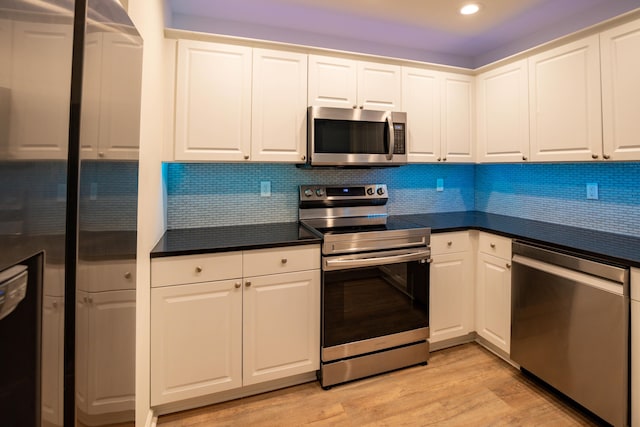 kitchen with decorative backsplash, light wood-type flooring, white cabinets, and appliances with stainless steel finishes