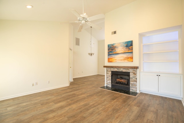 unfurnished living room with a stone fireplace, ceiling fan, high vaulted ceiling, dark hardwood / wood-style flooring, and built in shelves