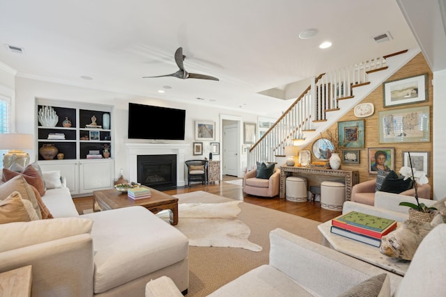 living area featuring visible vents, wood finished floors, a ceiling fan, and stairway