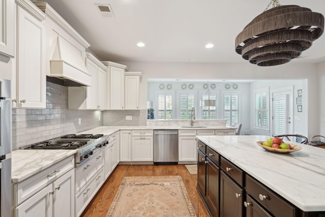 kitchen featuring a sink, white cabinets, a healthy amount of sunlight, and stainless steel appliances