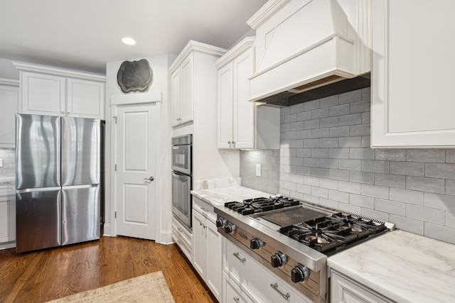 kitchen featuring dark wood-type flooring, custom exhaust hood, appliances with stainless steel finishes, and white cabinetry