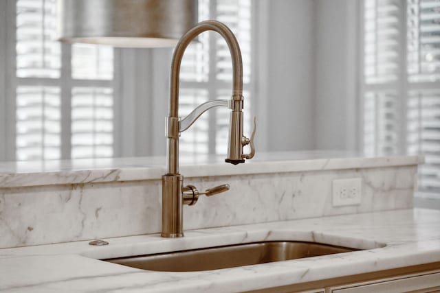 interior details featuring light stone counters and a sink