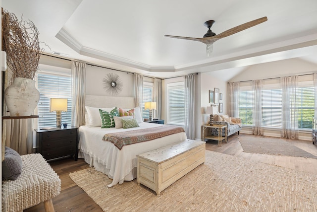 bedroom featuring ceiling fan, lofted ceiling, ornamental molding, wood finished floors, and a raised ceiling