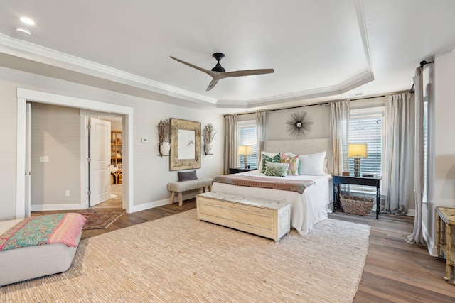 bedroom with ornamental molding, baseboards, a tray ceiling, and wood finished floors