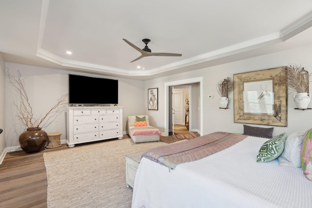 bedroom featuring crown molding, baseboards, light wood-type flooring, a tray ceiling, and recessed lighting