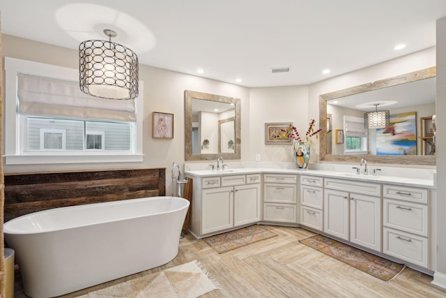 full bath with a sink, a soaking tub, recessed lighting, and double vanity