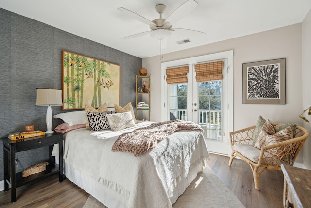 bedroom featuring visible vents, dark wood-style floors, french doors, access to exterior, and an accent wall