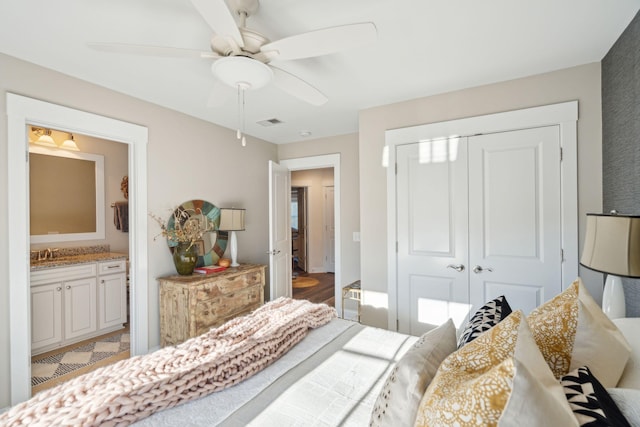 bedroom featuring visible vents, a ceiling fan, a sink, ensuite bath, and a closet