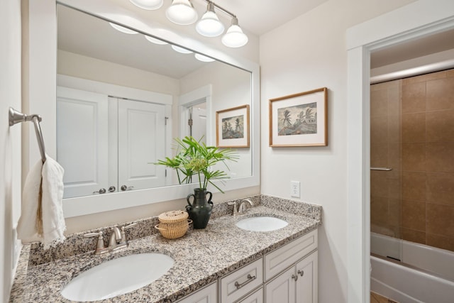 full bathroom with a sink, combined bath / shower with glass door, and double vanity