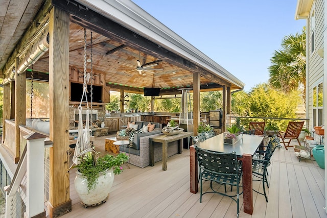 wooden deck with outdoor dining area, a ceiling fan, and outdoor lounge area