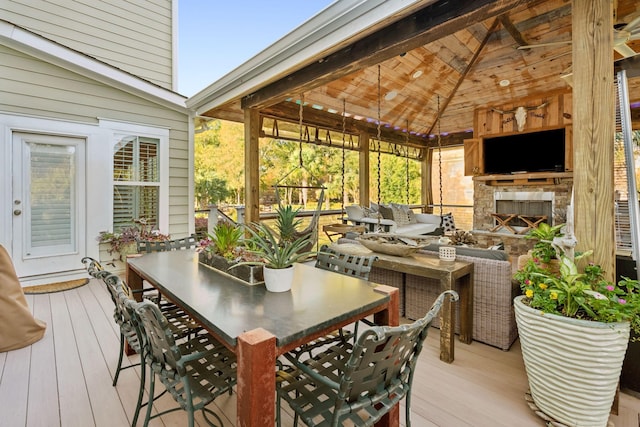 wooden deck with a stone fireplace and outdoor dining area